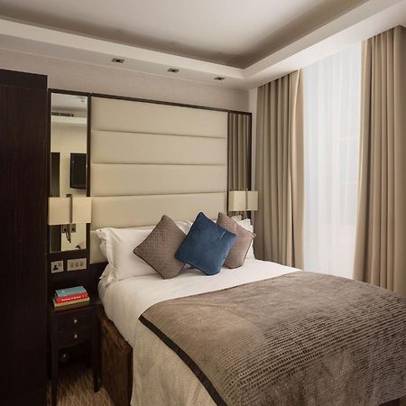 Montcalm Brewery Townhouse Hotel Londres Exterior foto The image shows a cozy bedroom. It features a comfortable double bed with a light-colored duvet and decorative pillows in shades of blue and gray. The headboard is upholstered in a soft material, and there are bedside lamps on either side of the bed.