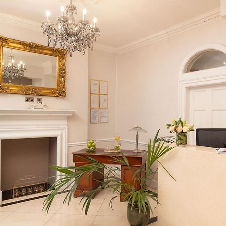 Montcalm Brewery Townhouse Hotel Londres Exterior foto The photo shows a stylish reception area. There is a decorative chandelier hanging from the ceiling, providing elegant lighting. A large, ornate mirror is mounted on the wall beside the fireplace, which features a simple, classic design. In front of 