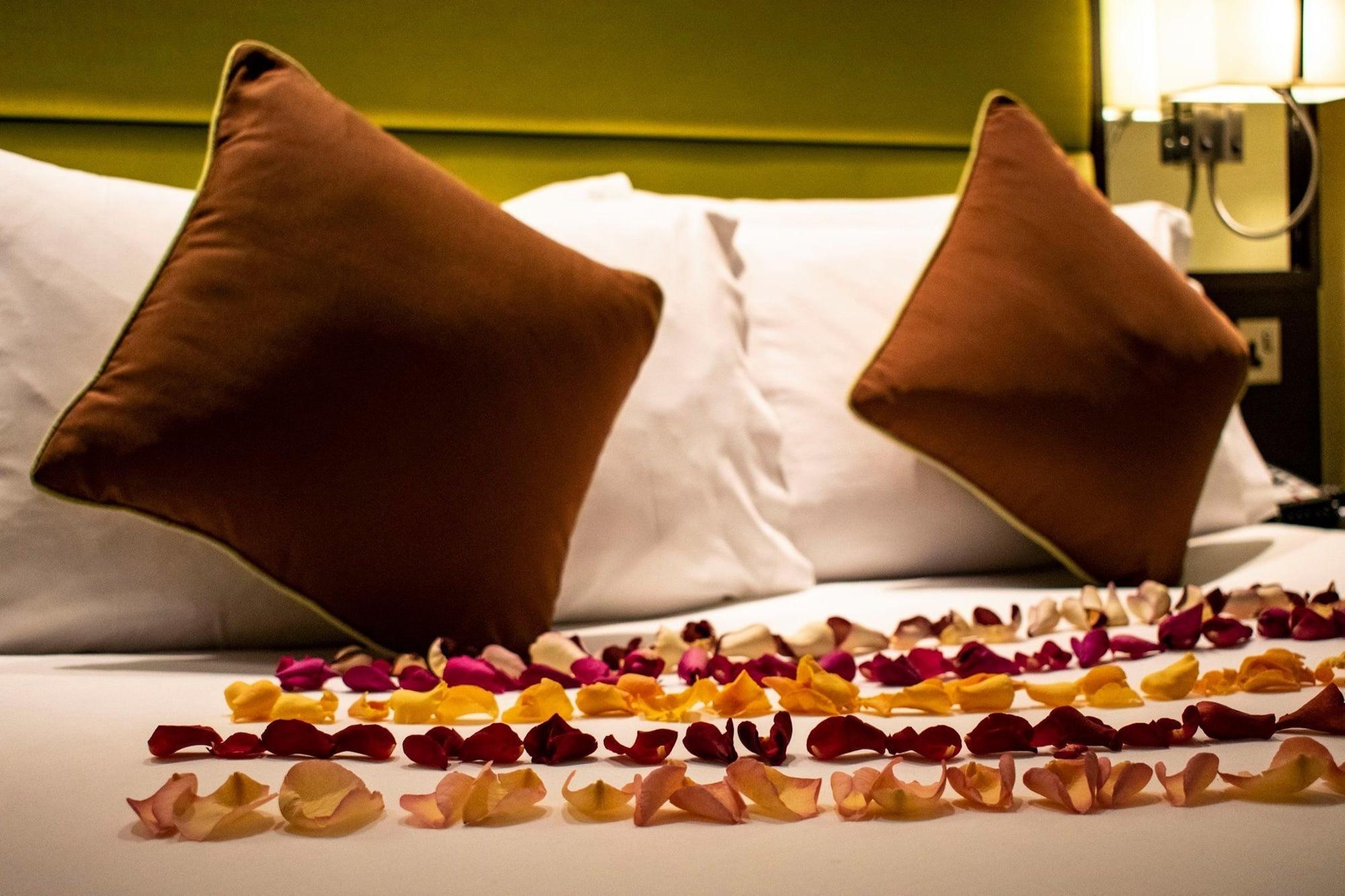Montcalm Brewery Townhouse Hotel Londres Exterior foto The photo shows a neatly arranged bed with two white pillows and brown decorative cushions. Scattered across the bed is a decorative display of flower petals in various colors, including pink, yellow, and orange, creating a romantic or tranquil ambia