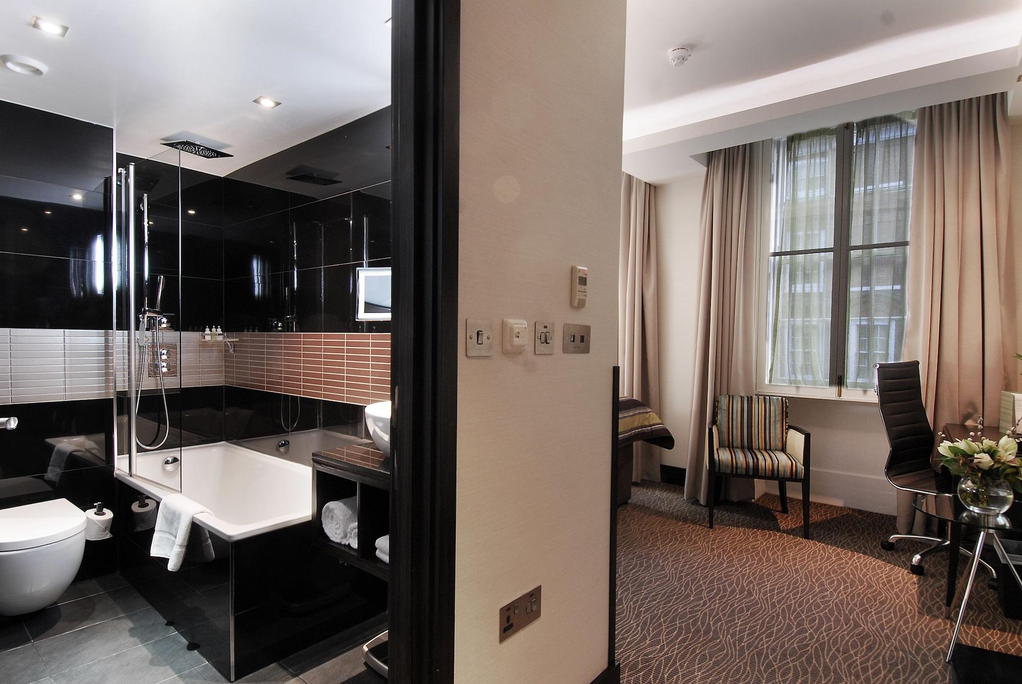 Montcalm Brewery Townhouse Hotel Londres Exterior foto The photo shows a modern hotel room that features an elegant bathroom on one side and a living area on the other. 

1. **Bathroom**: The bathroom is stylishly designed with a combination of black and white tiles. It includes a bathtub, a shower area 