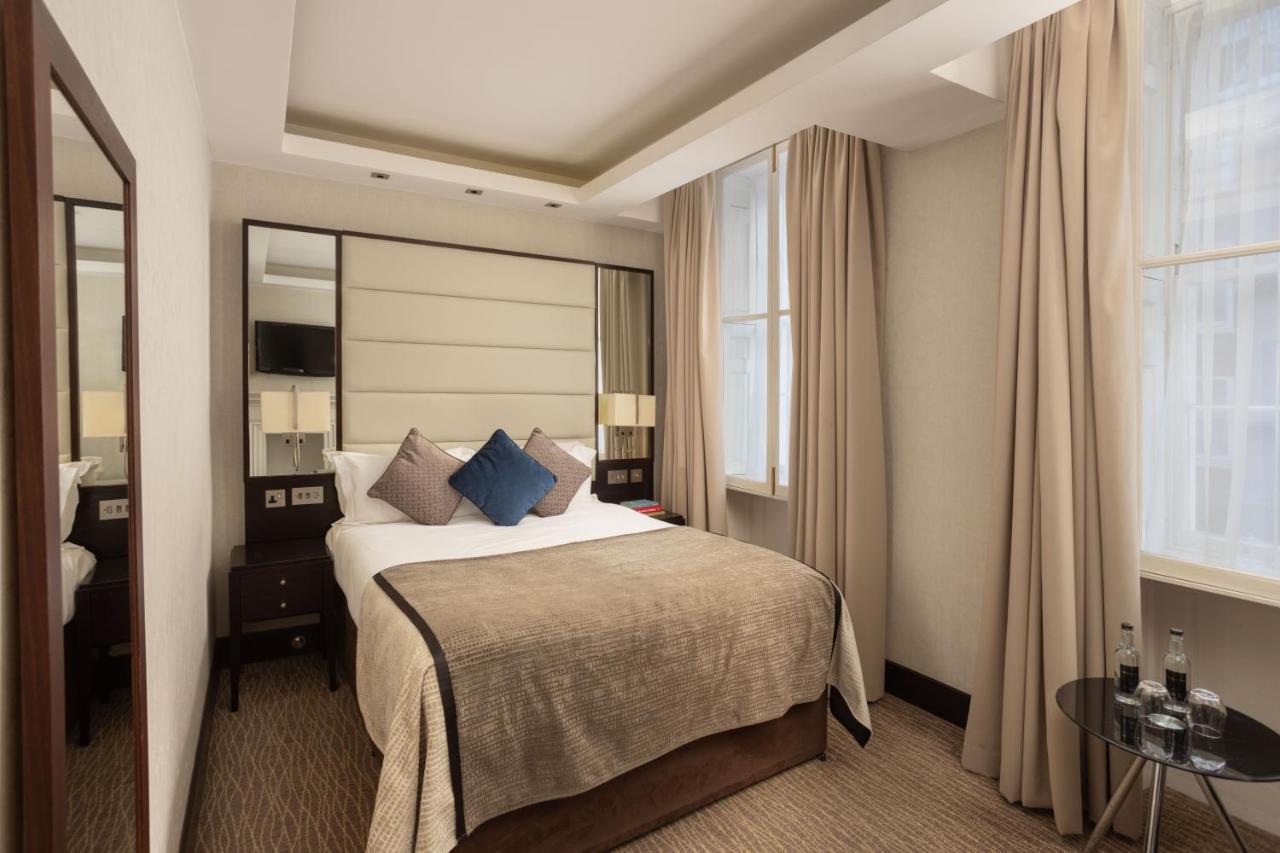 Montcalm Brewery Townhouse Hotel Londres Exterior foto The photo shows a cozy hotel bedroom. The room features a neatly made double bed with a beige bedspread and decorative pillows, including a blue one. There are bedside tables on either side of the bed with lamps. The walls are painted in a soft color