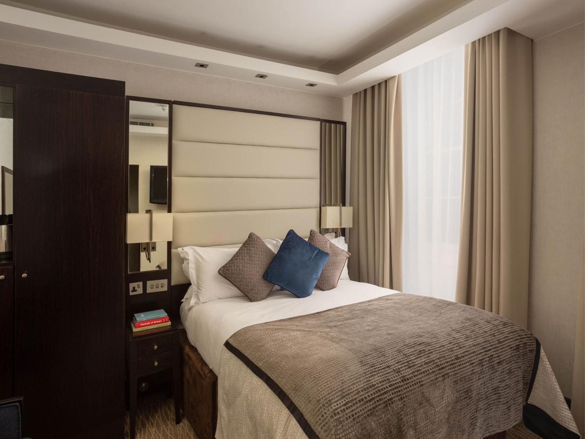 Montcalm Brewery Townhouse Hotel Londres Exterior foto The image shows a cozy bedroom. It features a comfortable double bed with a light-colored duvet and decorative pillows in shades of blue and gray. The headboard is upholstered in a soft material, and there are bedside lamps on either side of the bed.