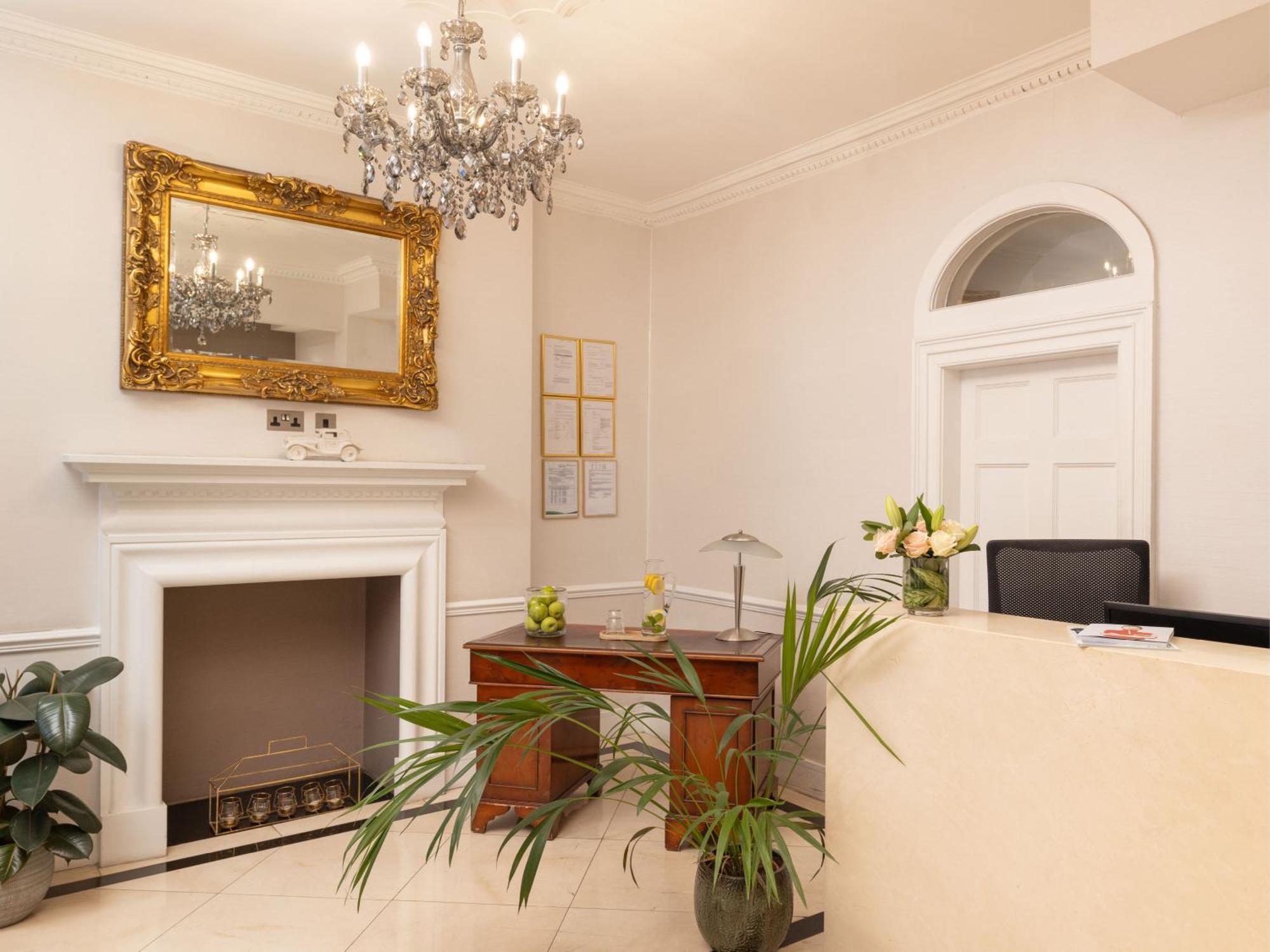 Montcalm Brewery Townhouse Hotel Londres Exterior foto The photo shows a stylish reception area. There is a decorative chandelier hanging from the ceiling, providing elegant lighting. A large, ornate mirror is mounted on the wall beside the fireplace, which features a simple, classic design. In front of 