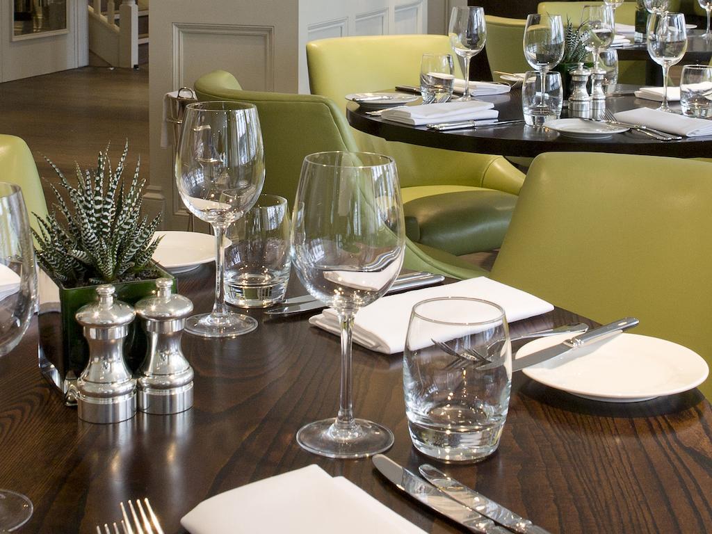 Montcalm Brewery Townhouse Hotel Londres Exterior foto The photo shows a dining setup in a restaurant. There are tables with a polished wooden surface and elegant place settings. Each setting includes multiple wine glasses and water glasses, neatly arranged with folded napkins. 

In the center, there are