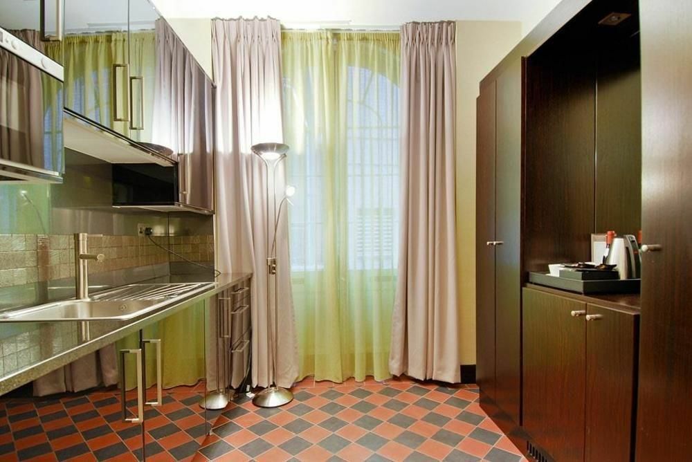 Montcalm Brewery Townhouse Hotel Londres Exterior foto The photo shows a modern kitchen area. There is metallic cabinetry and a stainless steel countertop with a sink. The walls are adorned with light-colored curtains that allow natural light to filter in, with one set in a soft purple hue and another in