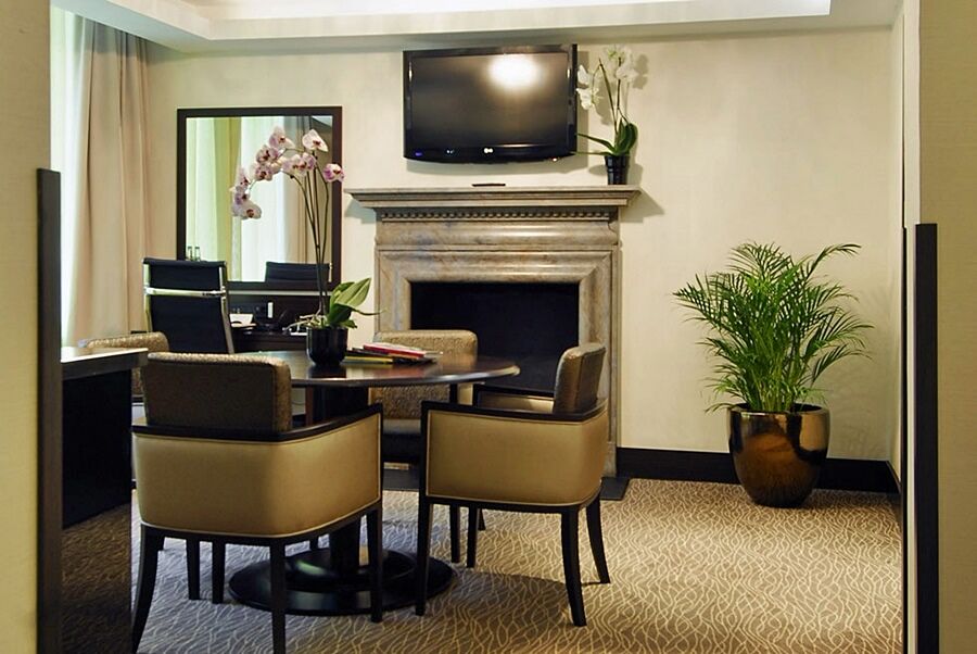 Montcalm Brewery Townhouse Hotel Londres Exterior foto The photo shows a modern and stylish room with a dining or meeting area. There is a round table surrounded by four upholstered chairs. A flat-screen television is mounted on the wall above a decorative fireplace. To the side, there is a mirror reflec