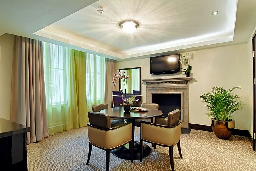Montcalm Brewery Townhouse Hotel Londres Exterior foto The photo shows a well-furnished room, likely a hotel suite or a modern living space. It features a round dining table with four comfortable chairs. The walls are adorned with light-colored decor, and there are large windows with sheer and solid curt