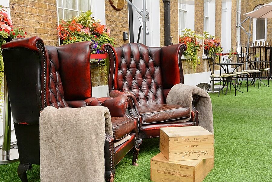 Montcalm Brewery Townhouse Hotel Londres Exterior foto The photo depicts two large, elegant armchairs with a classic design, featuring rich burgundy leather upholstery and button tufting. They are positioned in a cozy outdoor setting, with lush green artificial grass beneath them. Next to the chairs, the